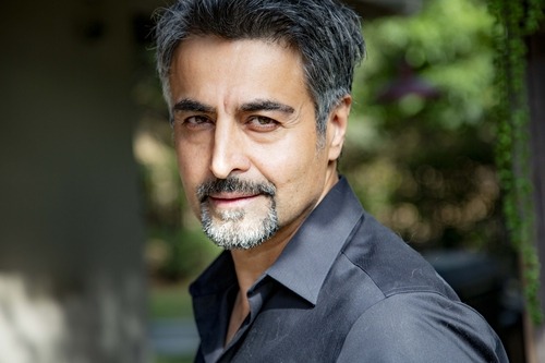 Nicholas Guilak — outdoor portrait in a dark shirt with his head turned, warm natural smile